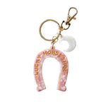 Pink horseshoe keychain with 'Lucky Horseshoe' text on a light background