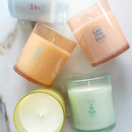 Four candles with zodiac-themed labels on a marble surface