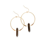Gold hoop earrings with dark cylindrical beads on a white background