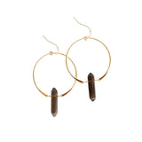 Gold hoop earrings with dark cylindrical beads on a white background
