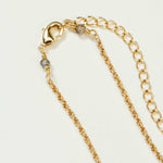 Gold necklace chain with a clasp and small grey stones on either side, resting on a white background