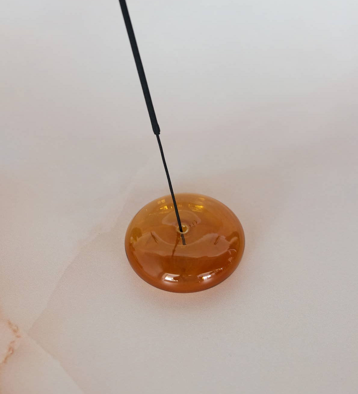 Round amber-colored object with a black rod on a white background