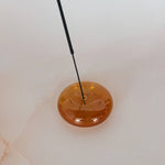Round amber-colored object with a black rod on a white background