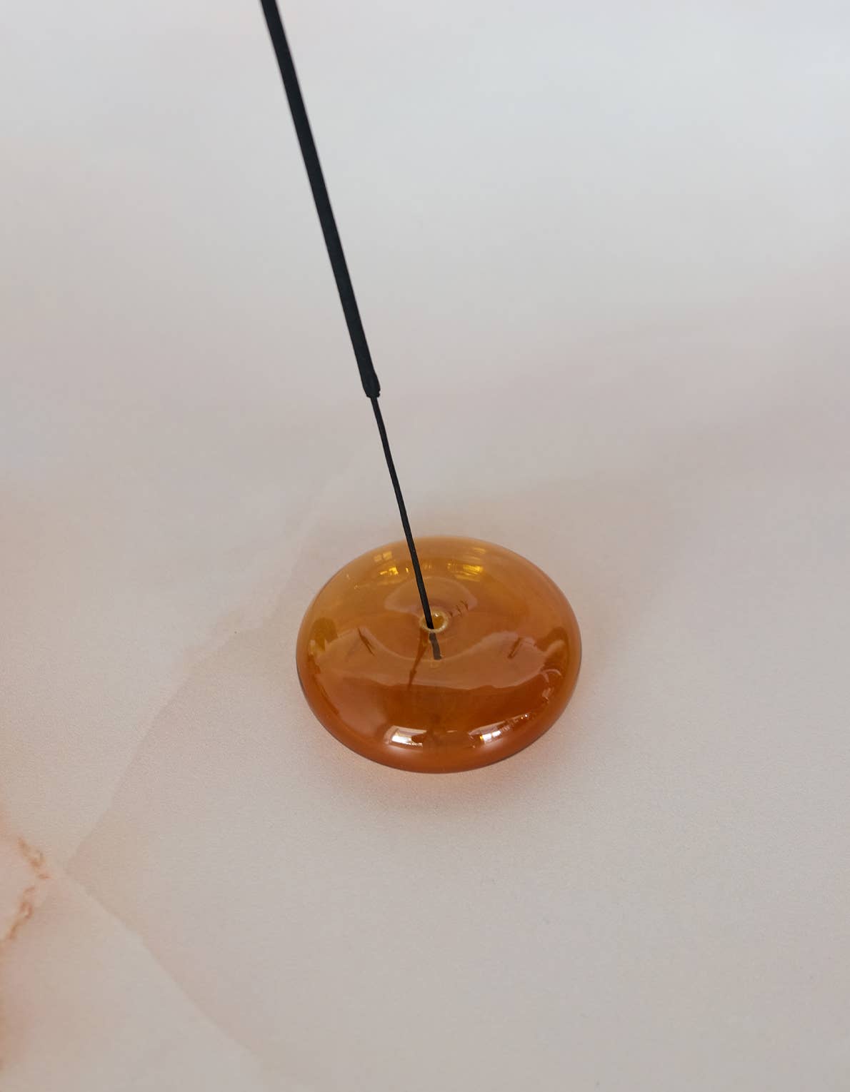 Round amber-colored object with a black rod on a white background