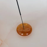 Round amber-colored object with a black rod on a white background