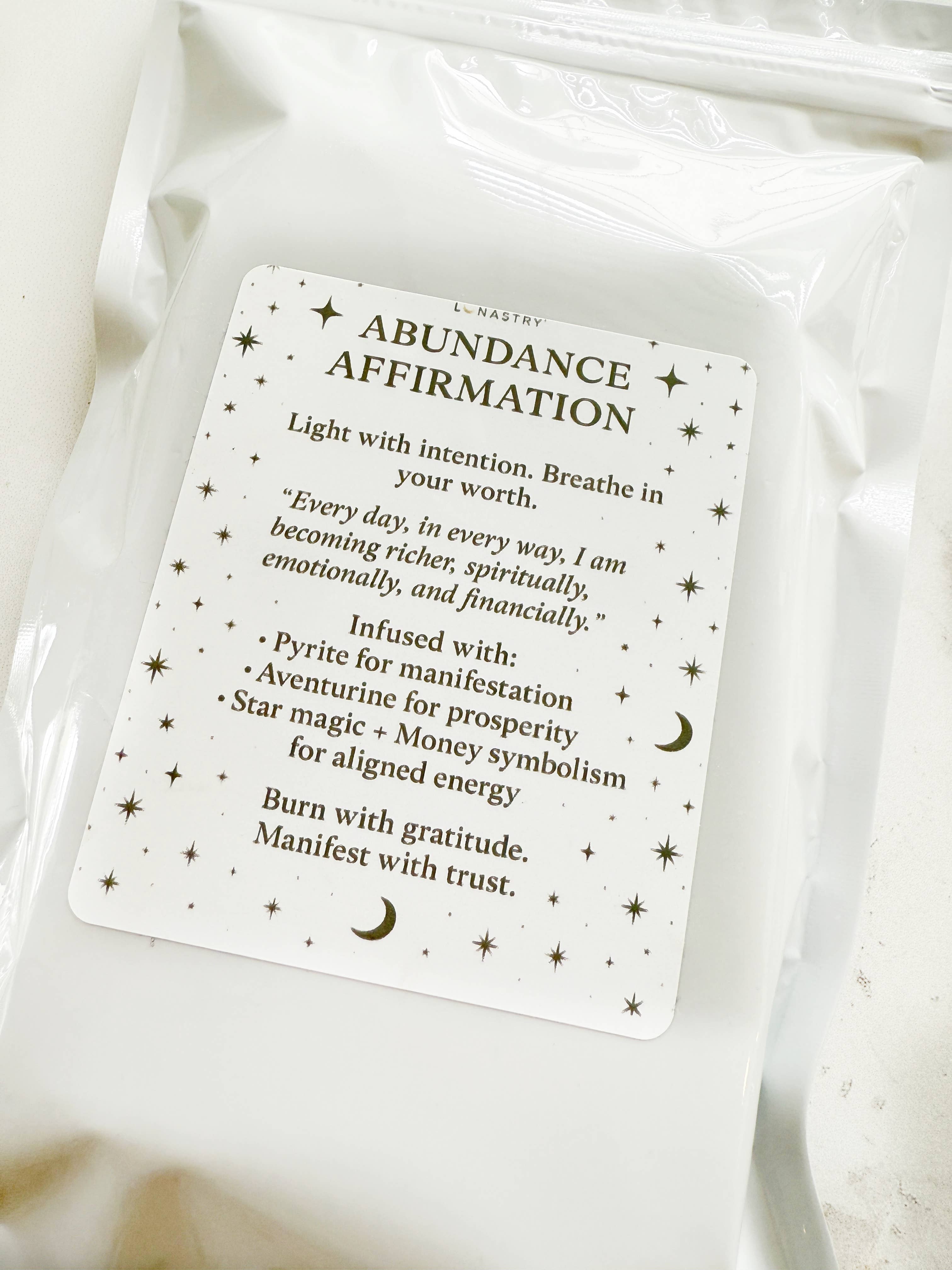 Abundance affirmation card on a white fabric background