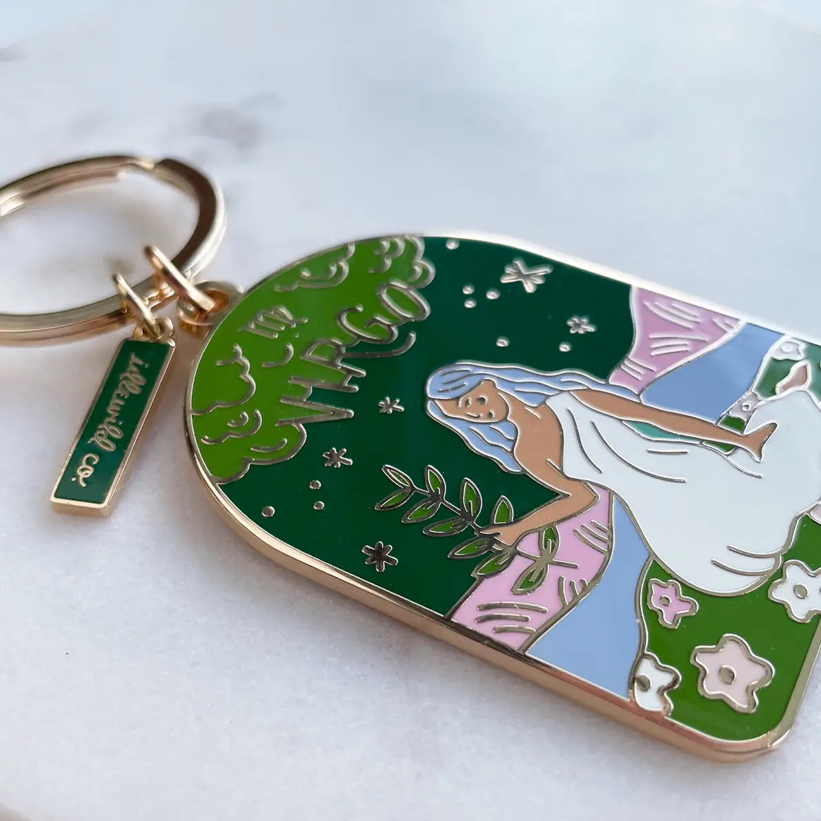 Close up of a colorful brass keychain with a woman sitting on a white background