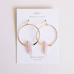 Gold hoop earrings with rose quartz stones on a Jaxxelly branded card.