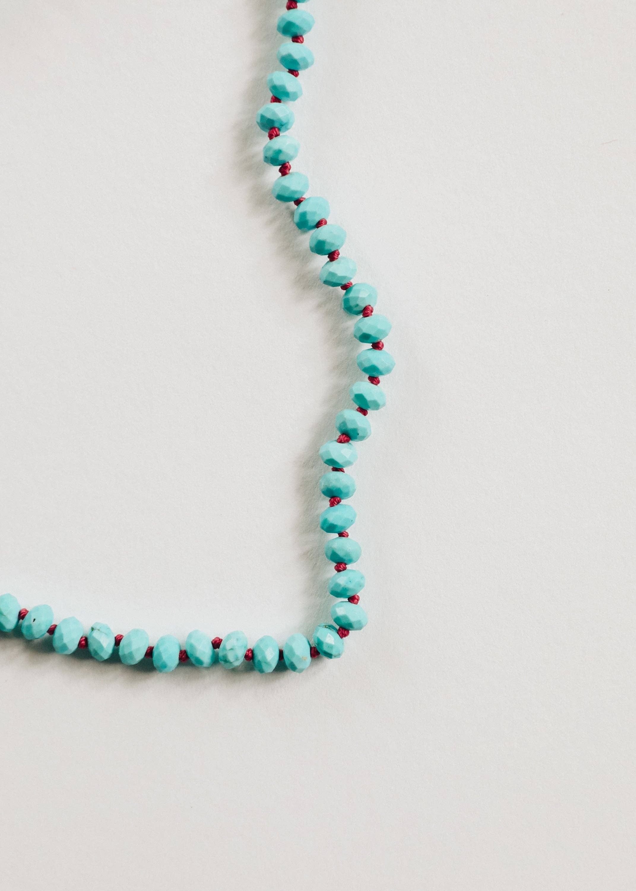Turquoise beaded necklace on a light gray background