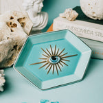 Hexagonal turquoise dish with decorative element on a light blue surface with decorative elements.