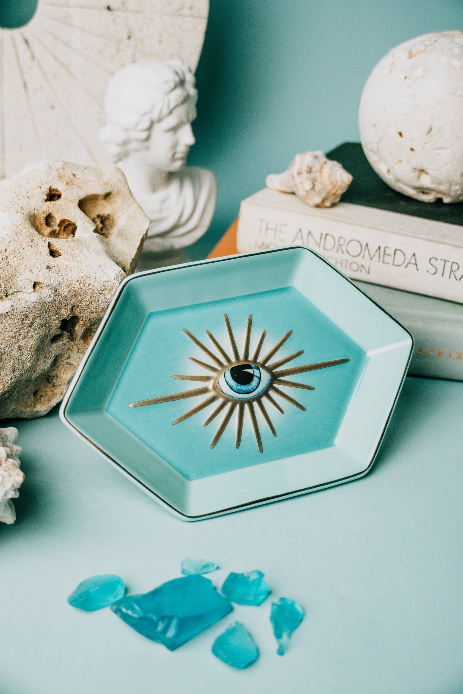 Hexagonal turquoise dish with decorative element on a light blue surface with decorative elements.