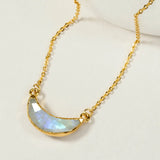 Gold necklace with an upward facing crescent moon moonstone pendant, displayed on a light background