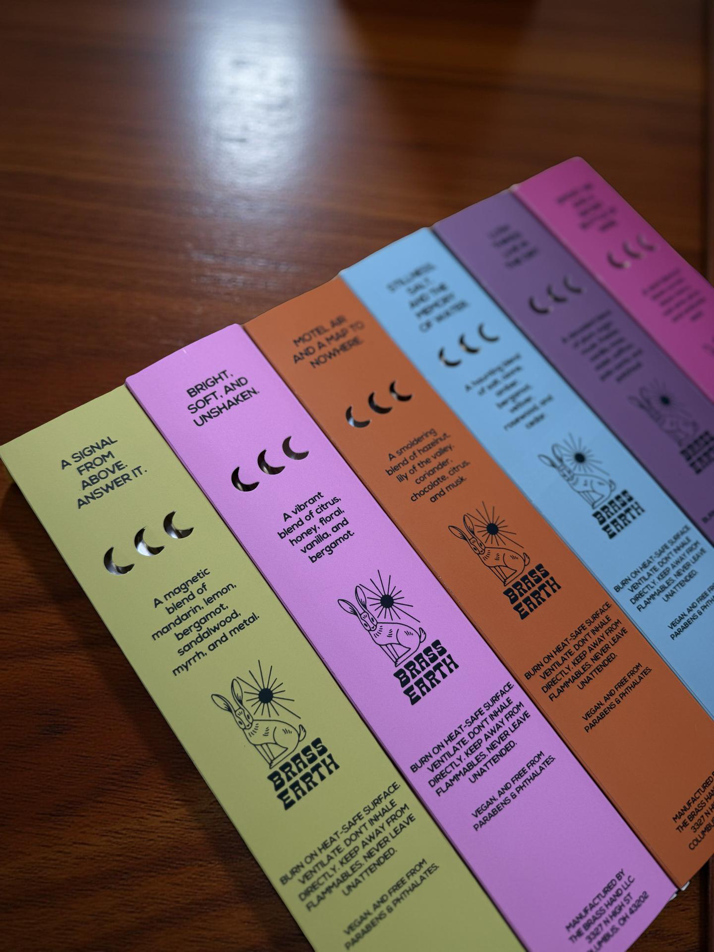 Set of colorful incense boxes with text and graphics on a wooden surface