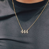 Gold necklace with '444' pendant on a person wearing a dark shirt