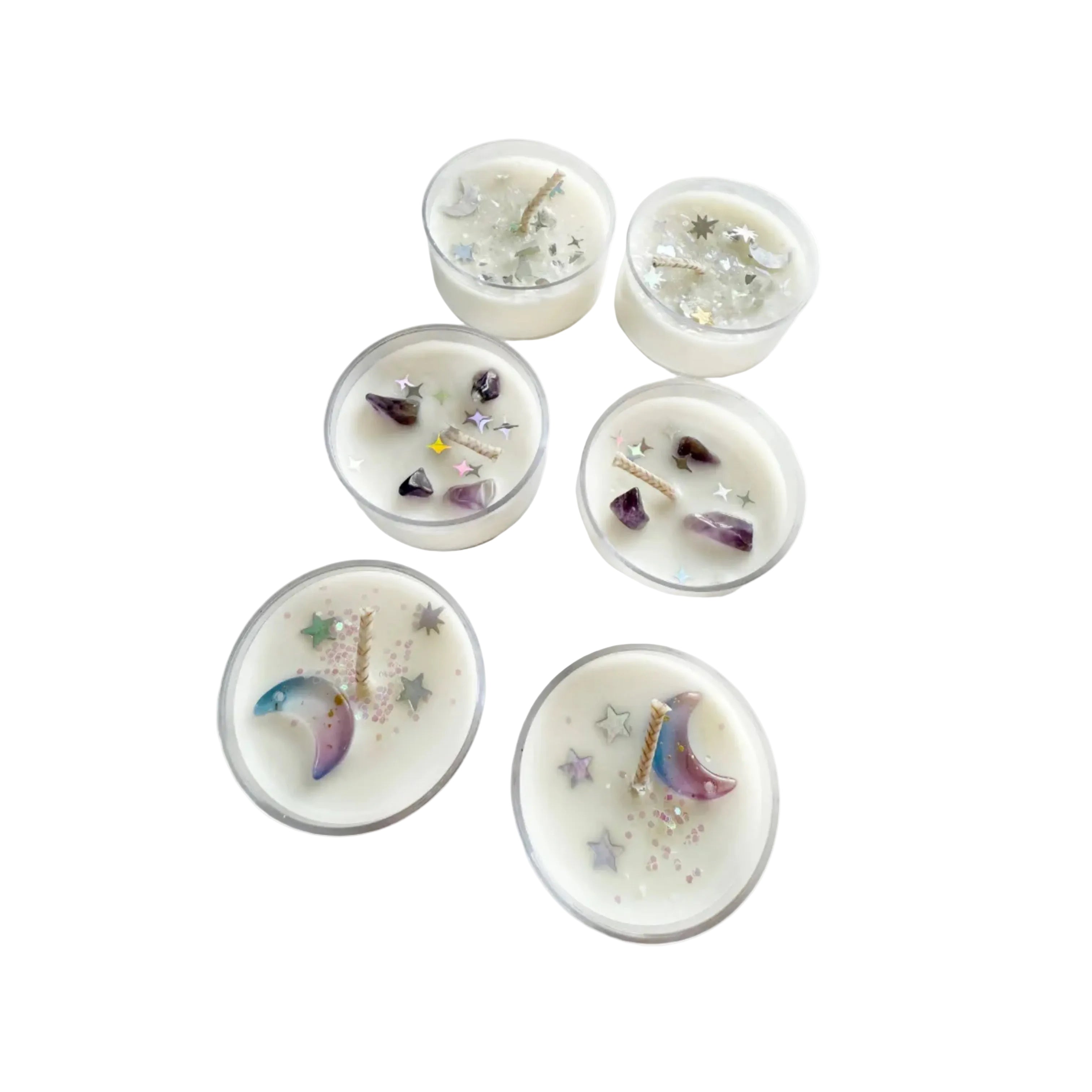 Six small tea light candles with decorative moons and glitter on a white surface