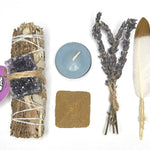 Collection of spiritual or ritual items for grief and healing including a smudge stick, candle, feather, and lavender on a white background.
