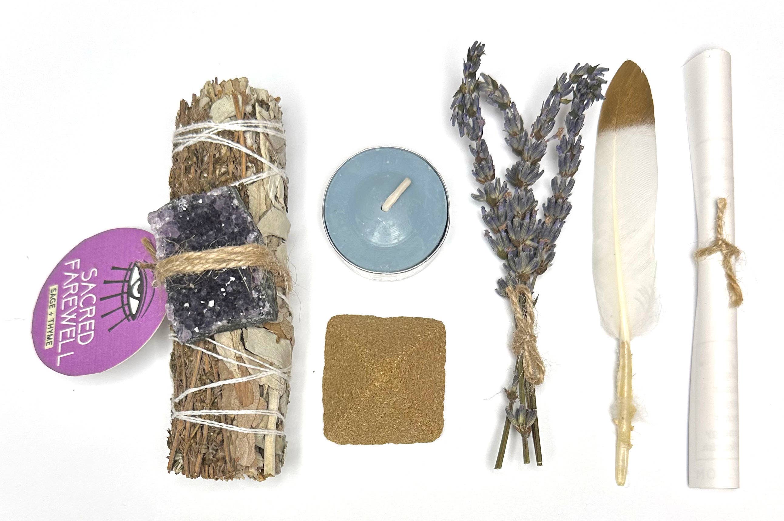Collection of spiritual or ritual items for grief and healing including a smudge stick, candle, feather, and lavender on a white background.