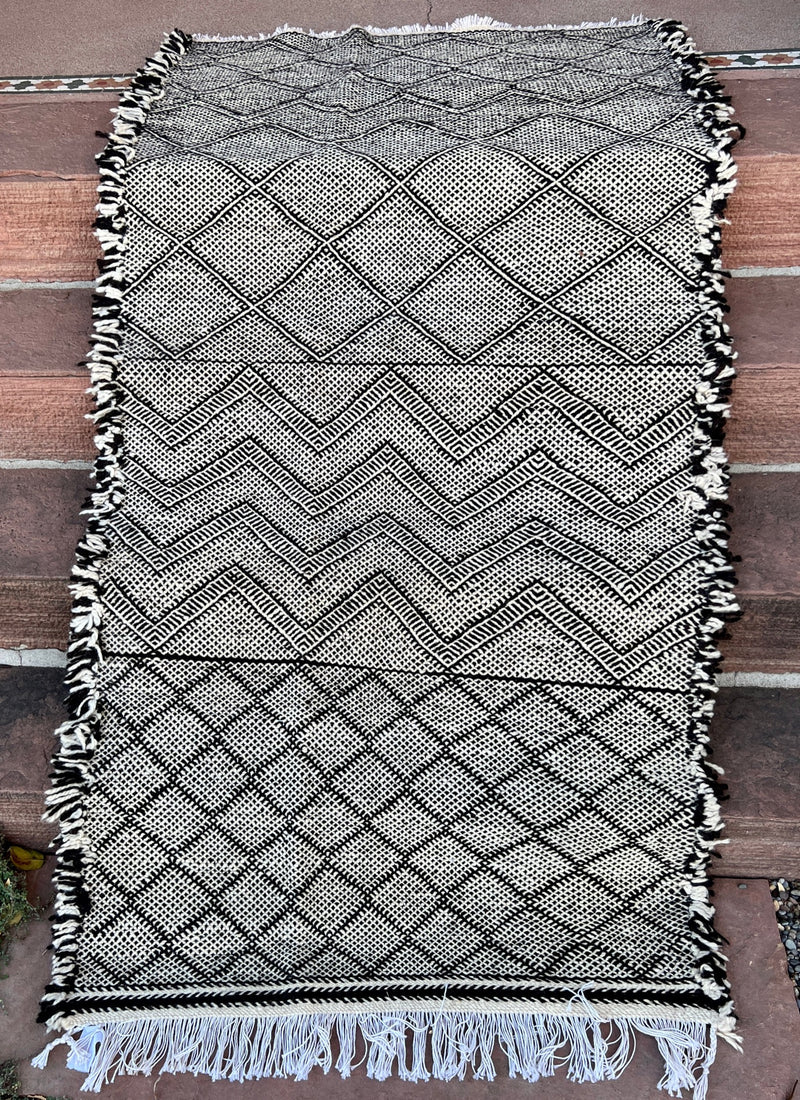 This incredible Moroccan hand-loomed wool rug has 3 sections of different patterns that all go together due to the black and cream wool being used.