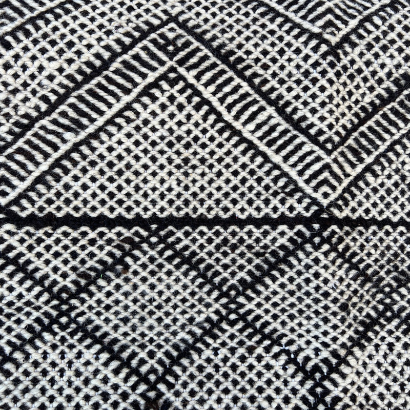 This incredible Moroccan hand-loomed wool rug has 3 sections of different patterns that all go together due to the black and cream wool being used.