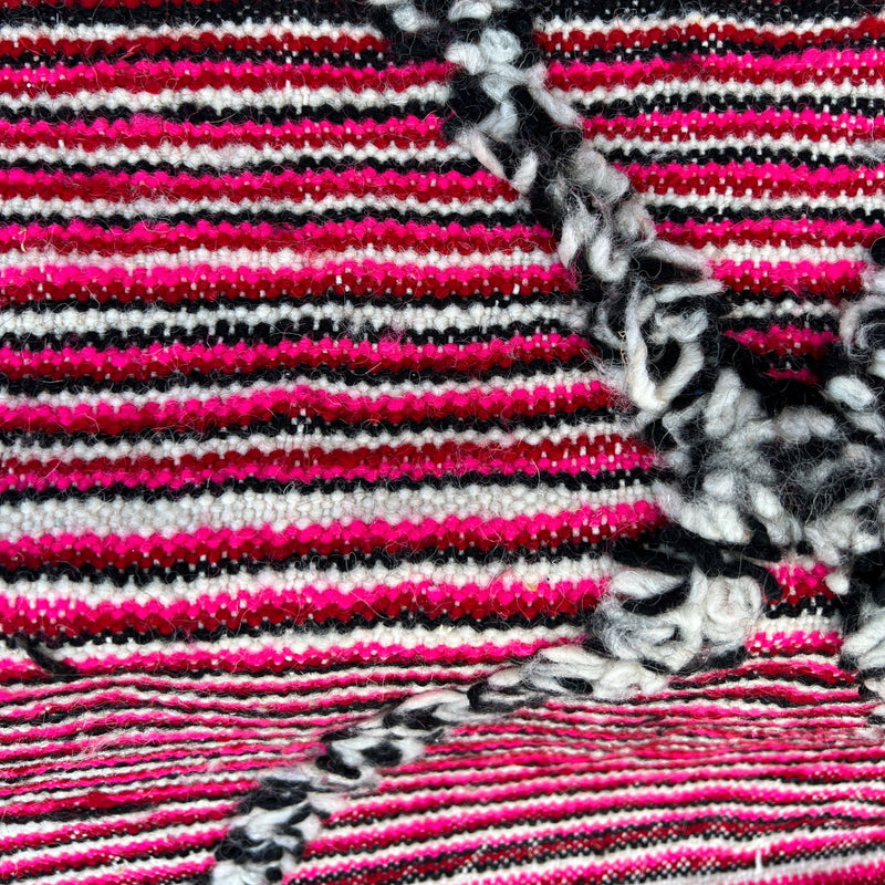 Moroccan hand loomed rug of 100% wool has hot pink, red, black and cream candy stripes with black and cream diamonds.