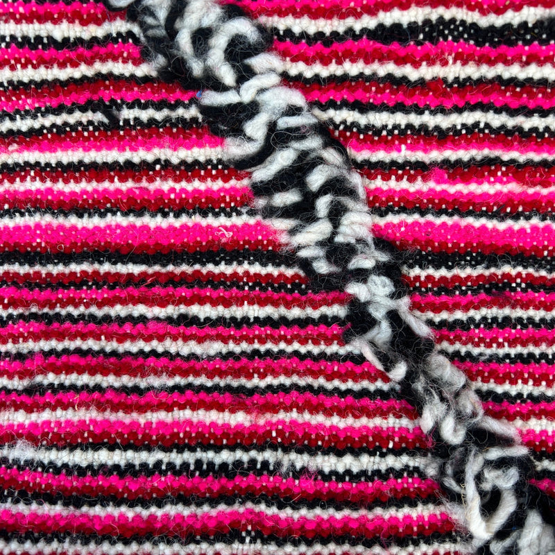 Moroccan hand loomed rug of 100% wool has hot pink, red, black and cream candy stripes with black and cream diamonds.