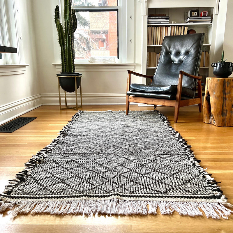 This incredible Moroccan hand-loomed wool rug has 3 sections of different patterns that all go together due to the black and cream wool being used.