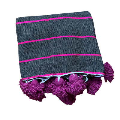 Moroccan black pom pom blanket with hot pink stripes and bright maroon large pom poms. Currently, these kind of heavy quality Berber throw-on blankets are popular in hotels and Moroccan riads and we understand why.
