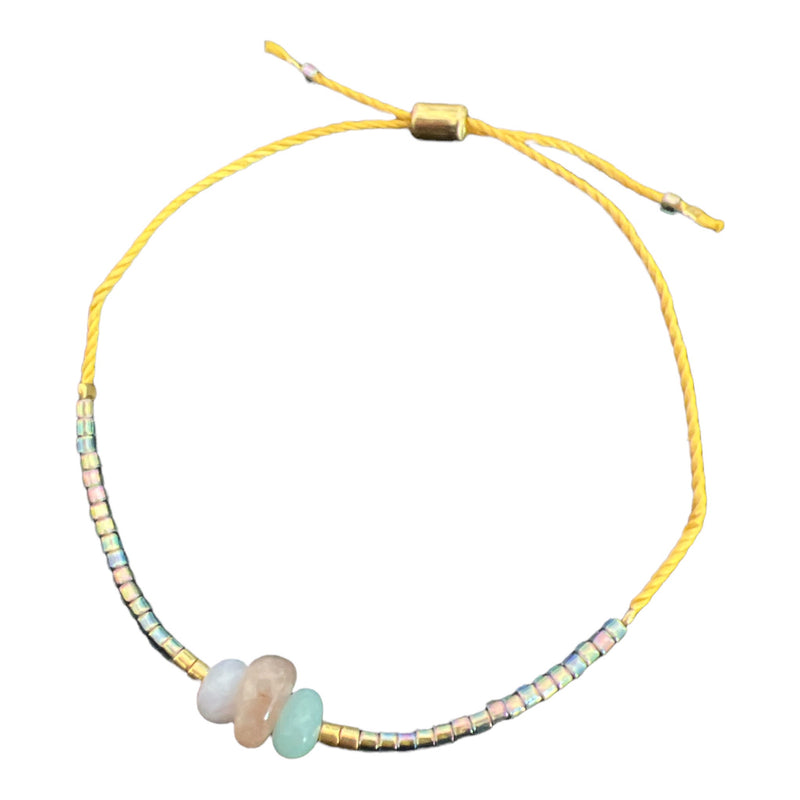 This calming + anti-anxiety bracelet holds iridescent beads and chosen stones on an adjustable gold thread. 